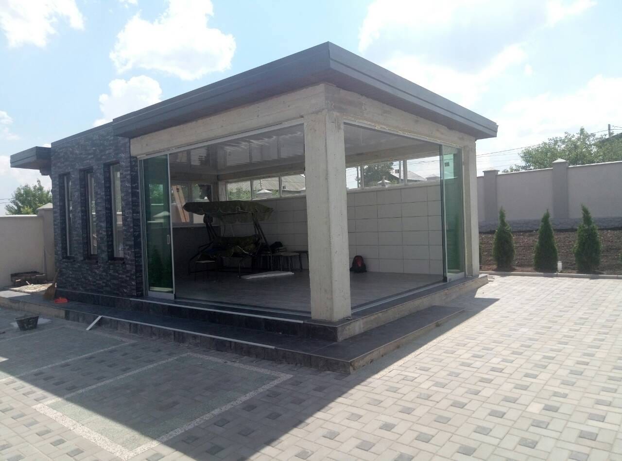 מבנה גינה עם קירות זכוכית וחיפוי אבן, מרוצף באבן משתלבת